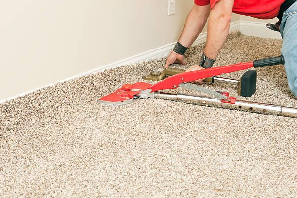 Technician performing carpet stretching with professional equipment.