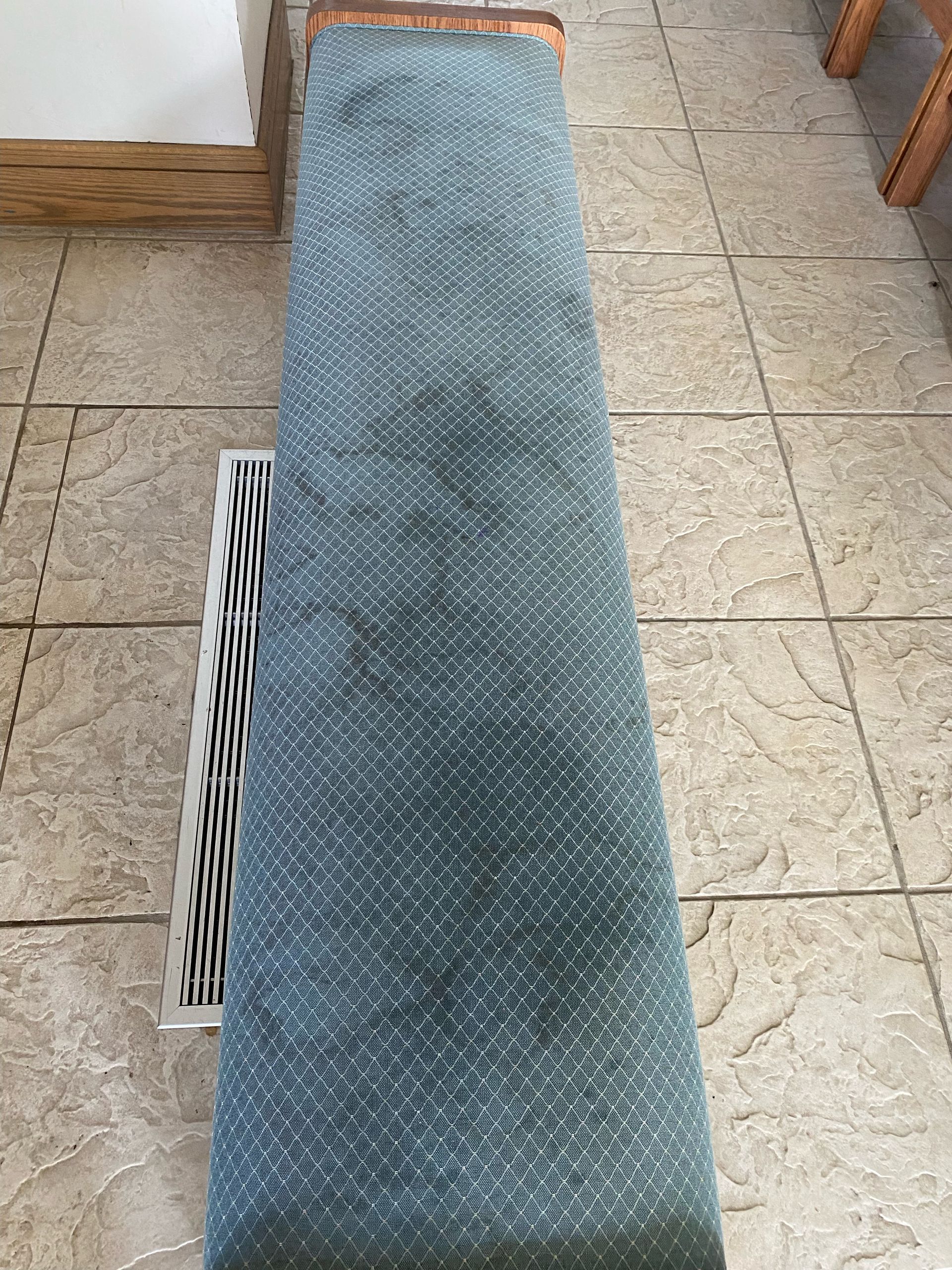Blue woven runner rug rolled up on a tiled floor.