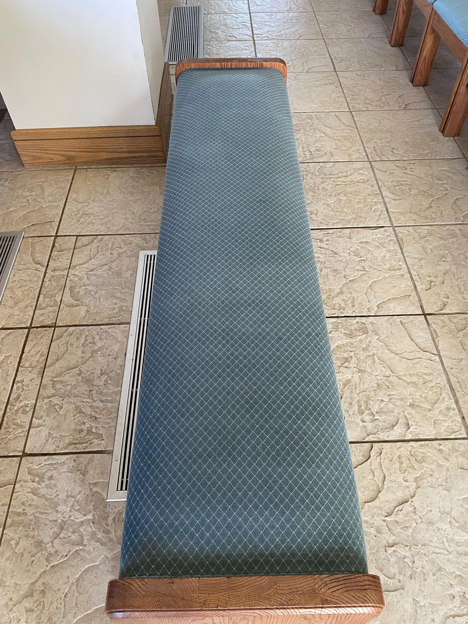 Blue and brown carpeted bench on a tiled floor, likely indoors.