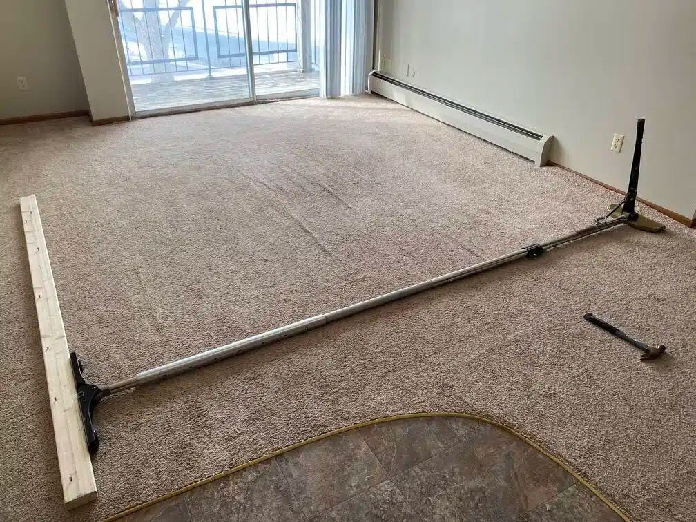 Professional installer using carpet stretching tools during home carpet repair. Professional installer using carpet stretching tools during home carpet repair.