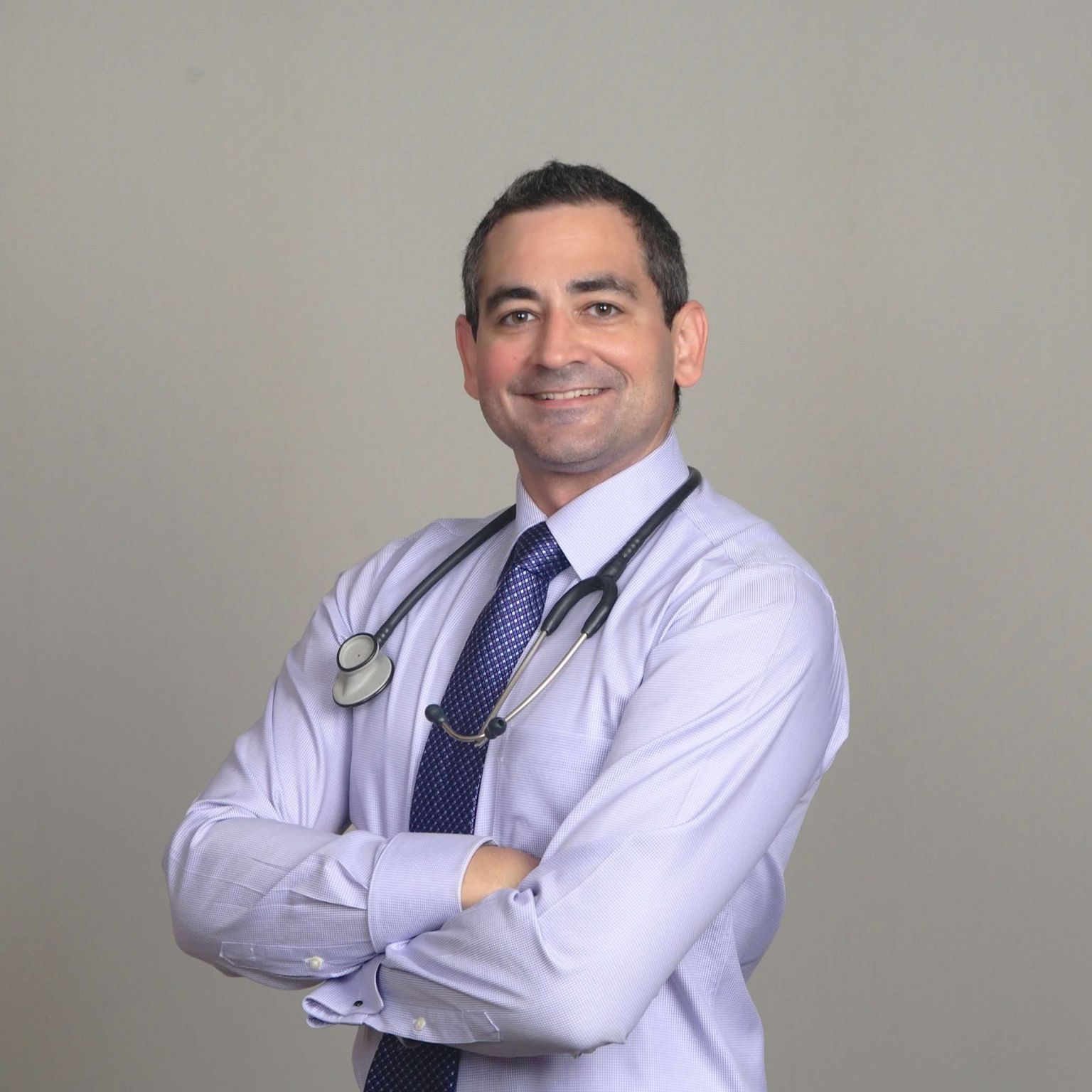 A man in a white shirt and tie with a stethoscope around his neck.