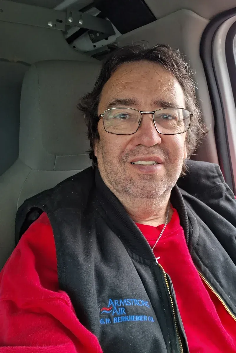 A man wearing glasses and a red shirt is sitting in a car.