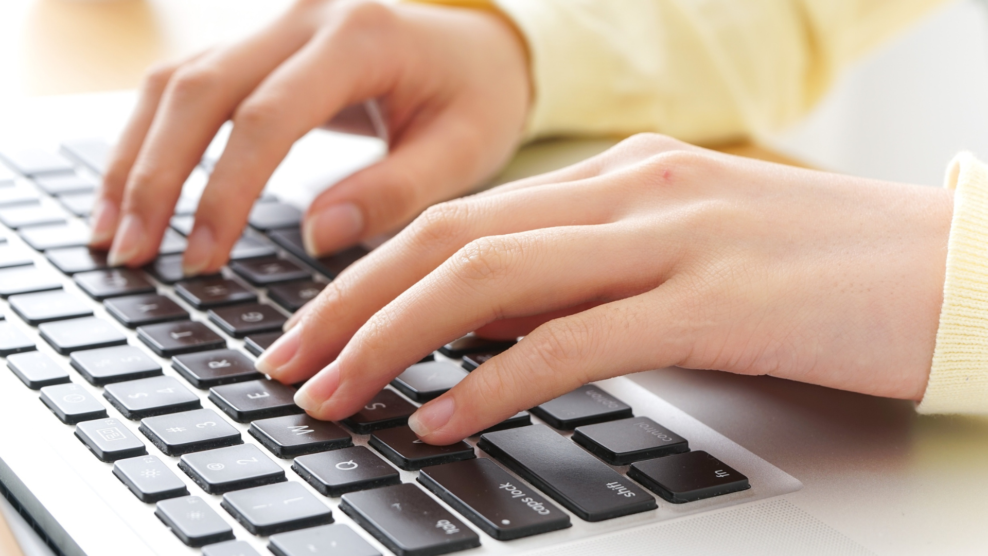 Hands typing on a laptop keyboard; close-up view.