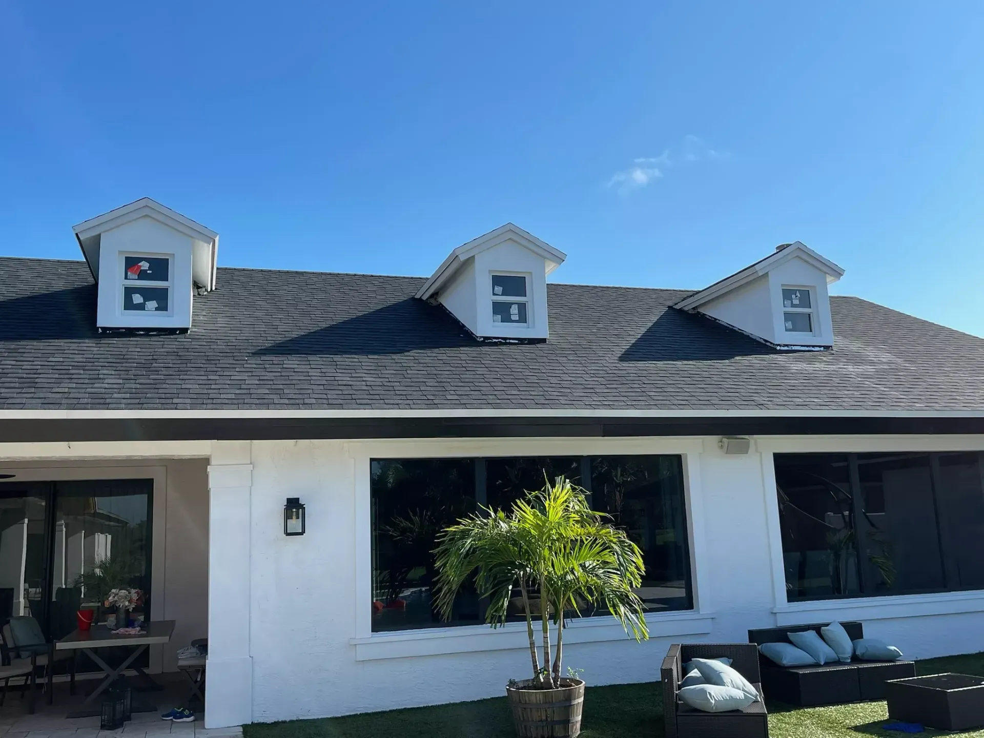 A white house with a black roof and a lot of windows
