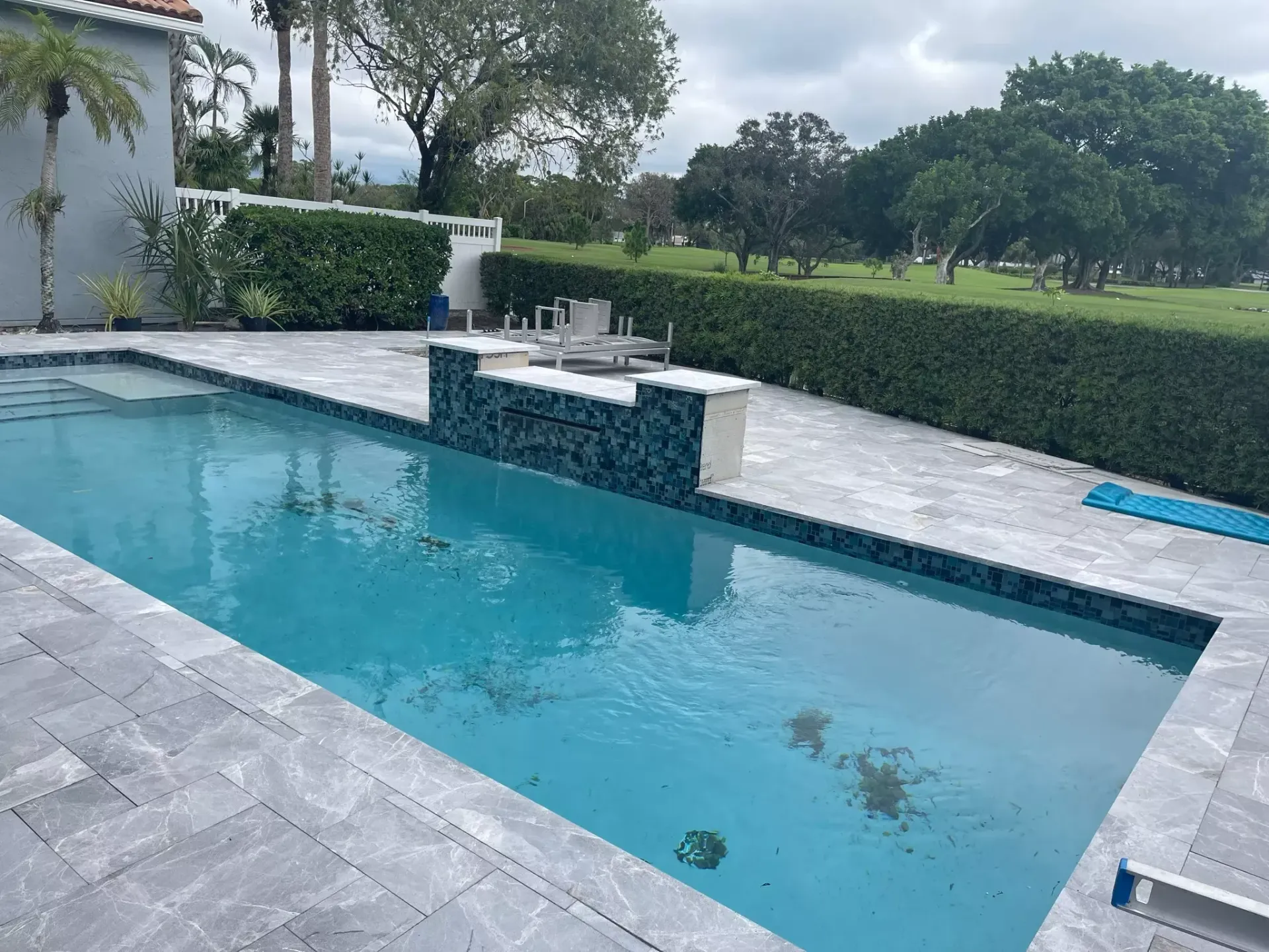 A large swimming pool with a golf course in the background