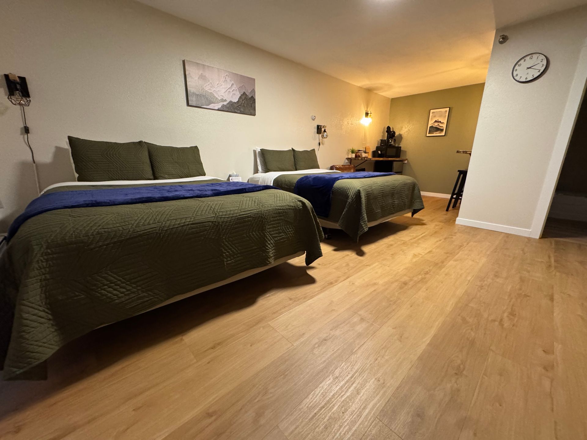 Two queen beds in a room with wood flooring and a desk area.