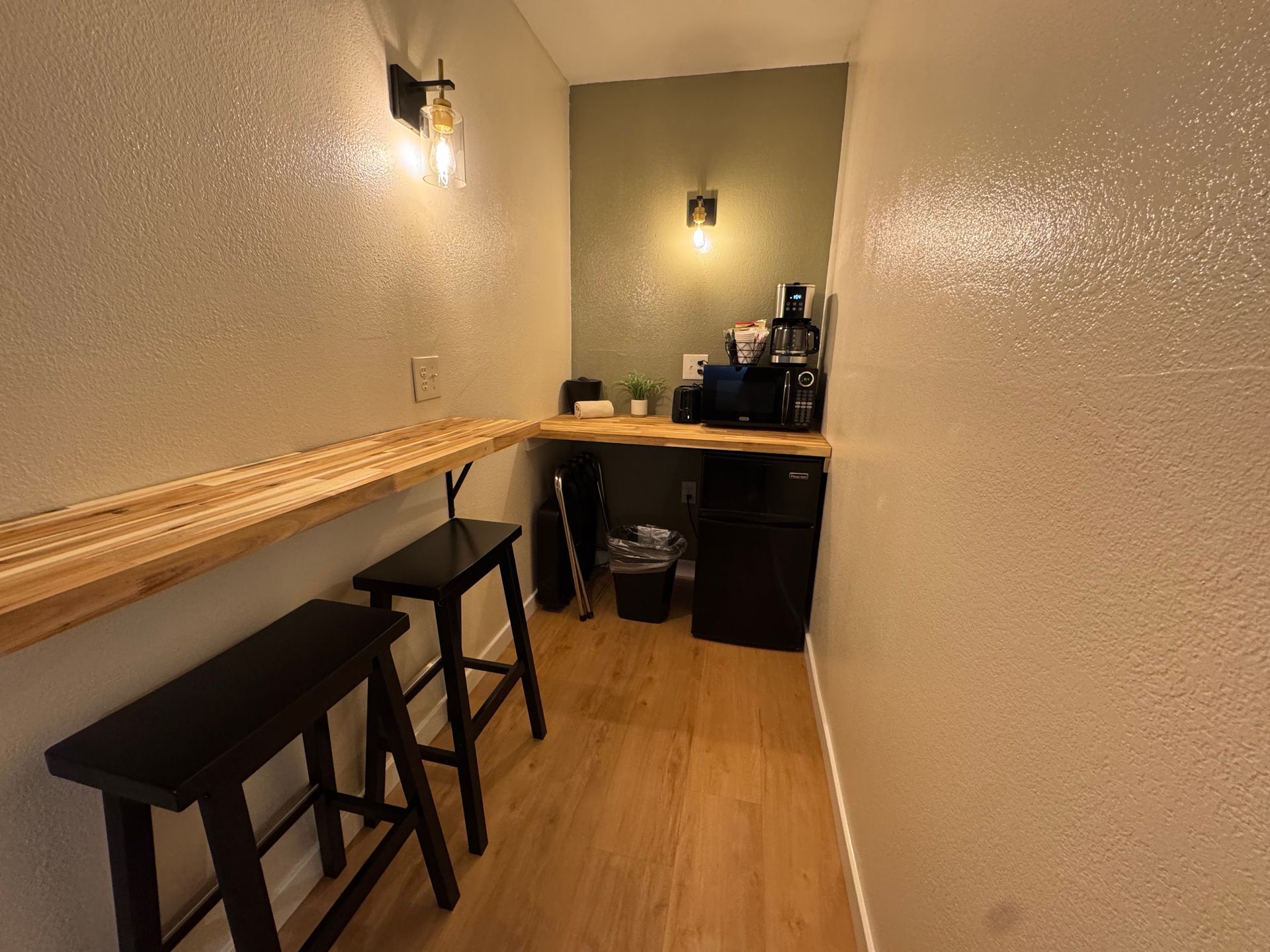 Small kitchen area with a counter, stools, and appliances.