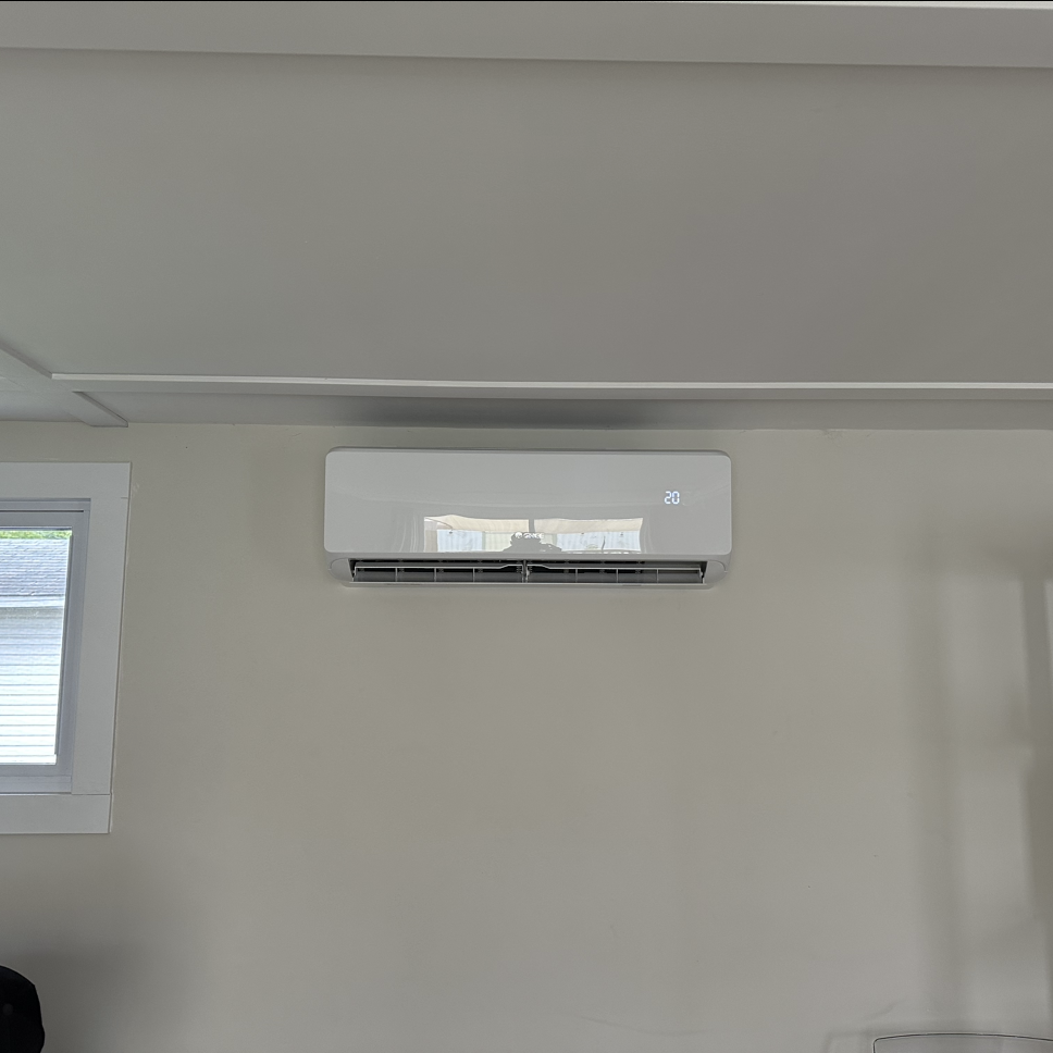 Un climatiseur blanc est accroché à un mur à côté d'une fenêtre.