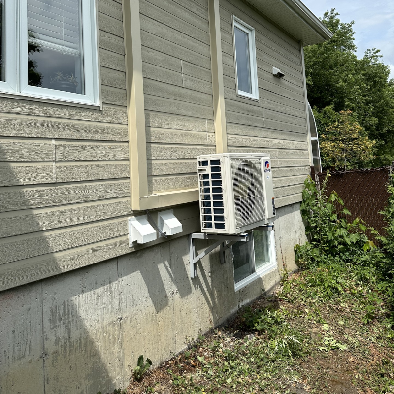 Un climatiseur blanc est monté sur le côté d'une maison.