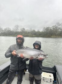 A man and a boy are holding a large fish on a boat.