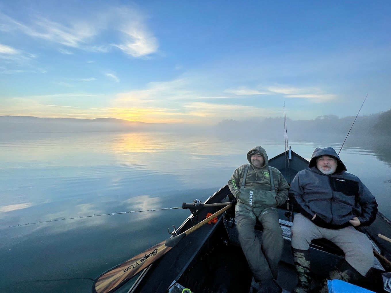 Two men are sitting in a boat on a lake.