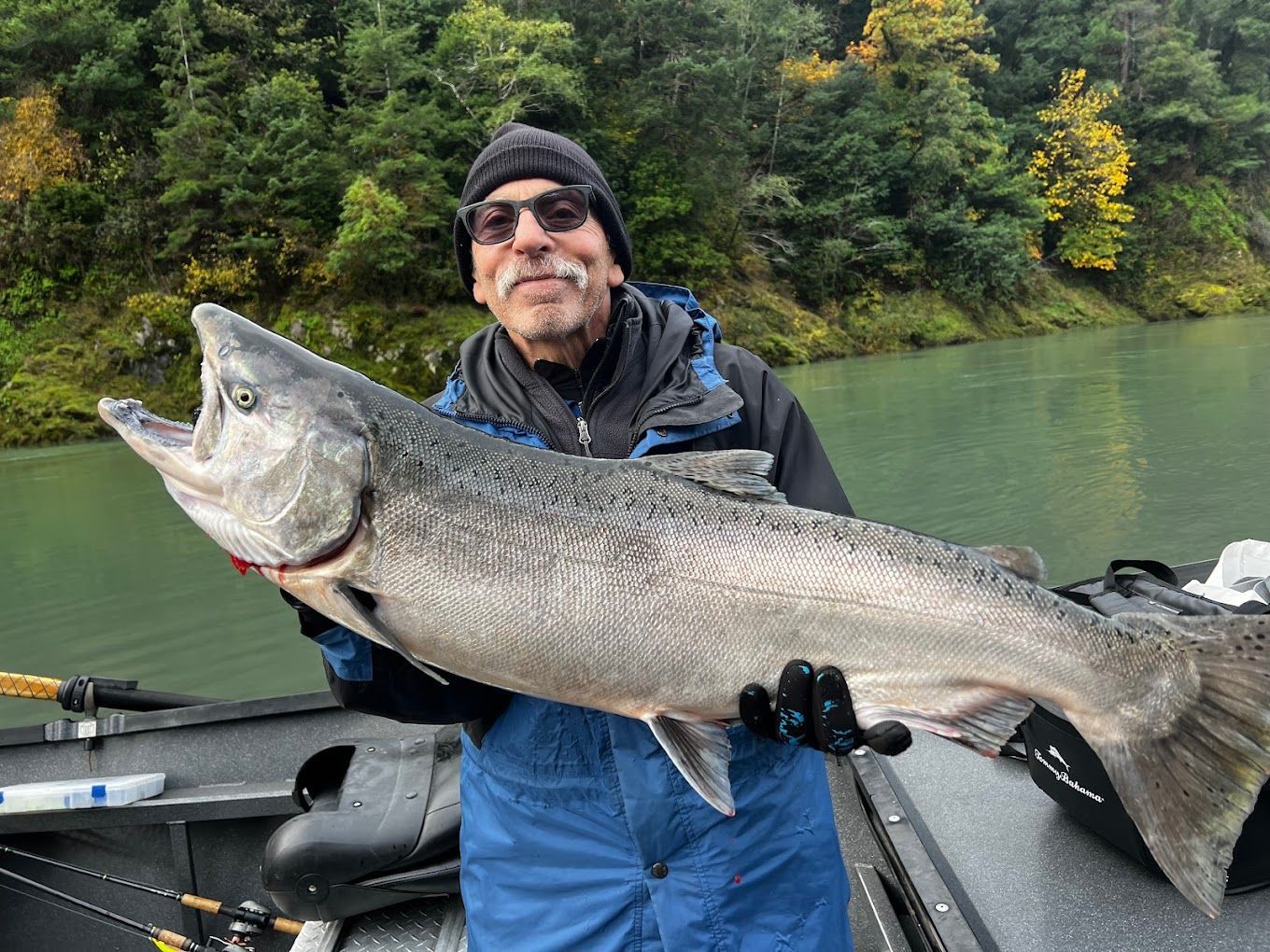 A man is standing on a boat holding a large fish.