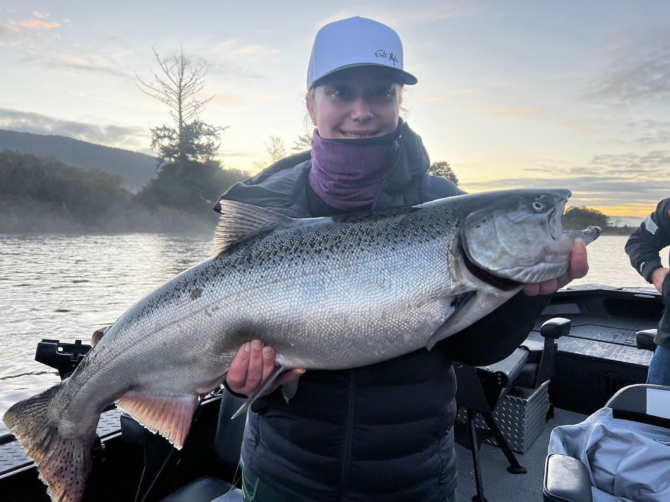 A woman is holding a large fish on a boat.