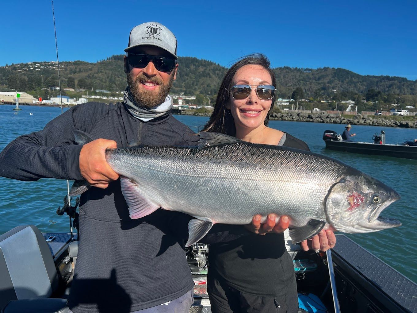 A man and a woman are holding a large fish on a boat.