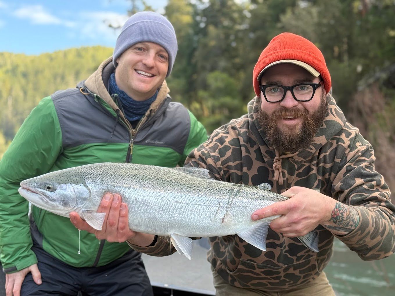 Two men are holding a large fish in their hands.