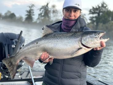 A woman is holding a large fish in her hands on a boat.