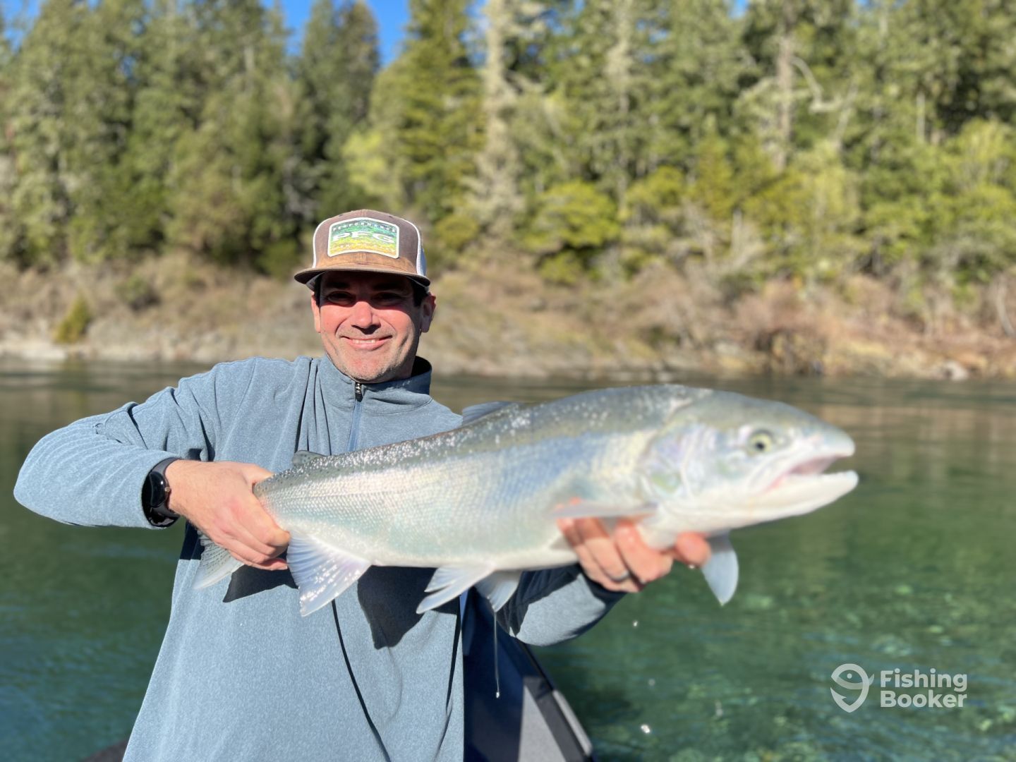 A man is holding a large fish in his hands in a river.