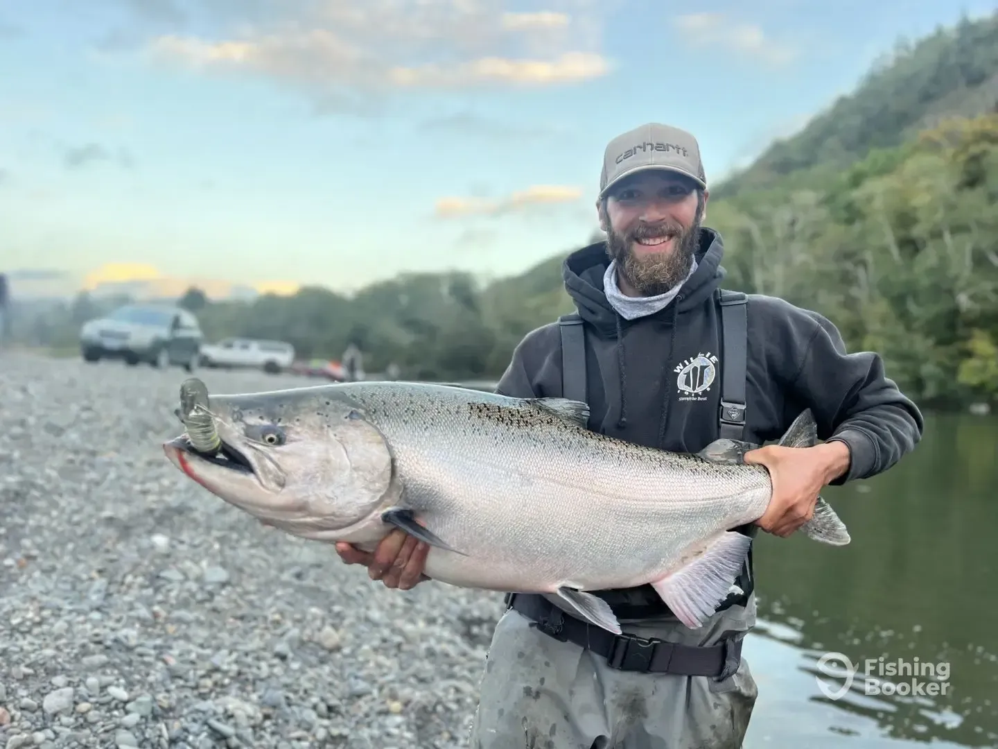 A man is holding a large salmon in his hands.