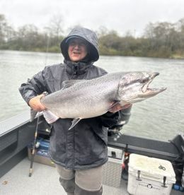A woman is holding a large fish on a boat.