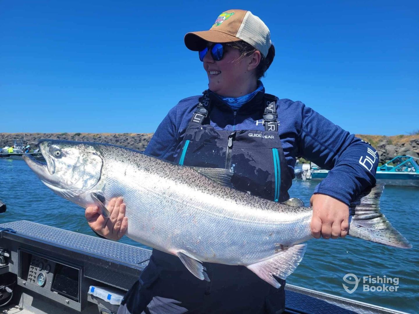 A woman is holding a large salmon on a boat.