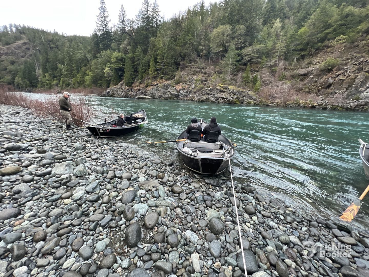 A couple of boats are sitting on the shore of a river.