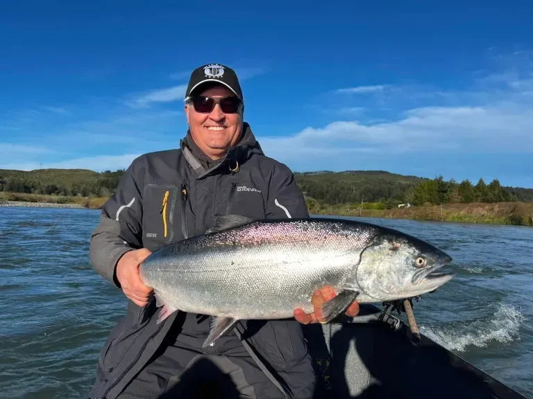 A man is sitting in a boat holding a large fish.