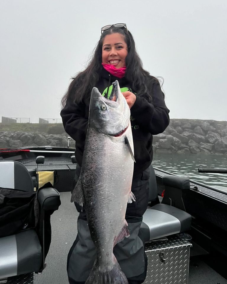 A woman is holding a large fish on a boat.