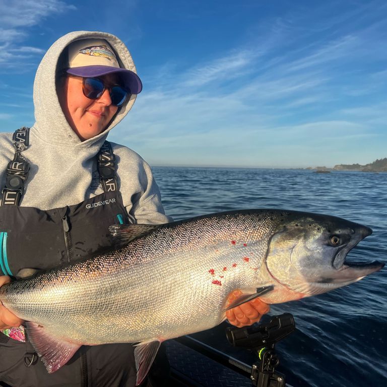 A woman in a hoodie is holding a large fish