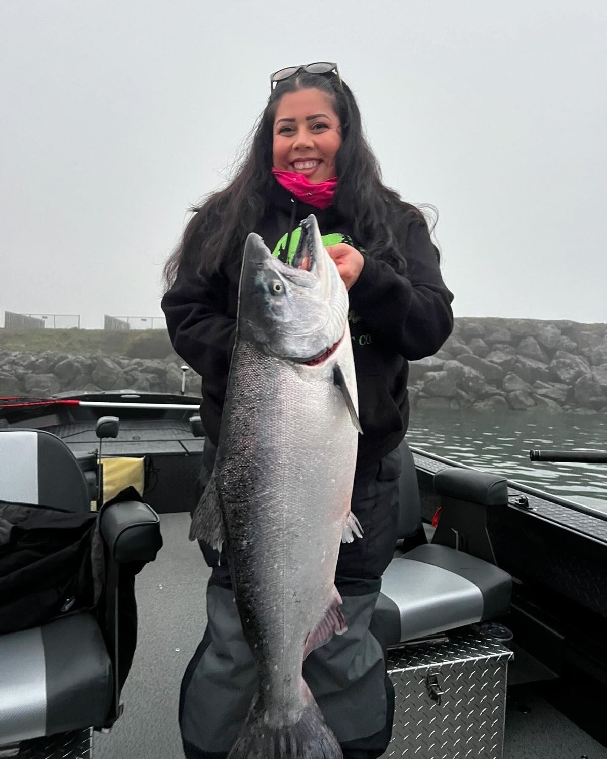 A woman is holding a large fish on a boat.