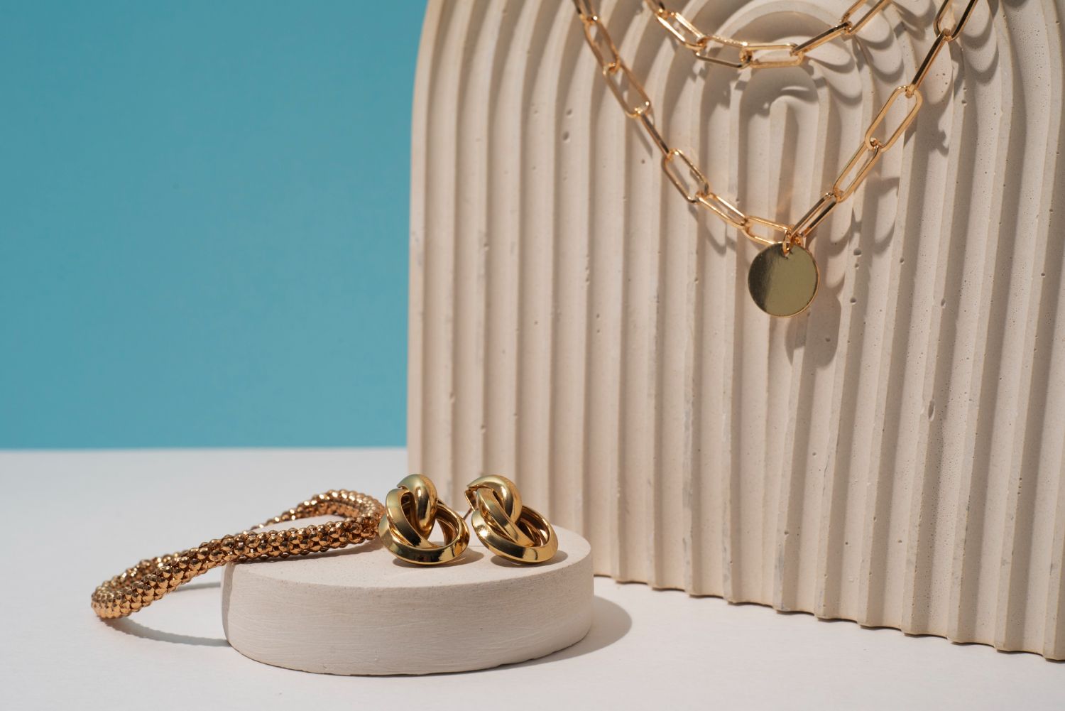 A necklace and earrings are sitting on a white podium.