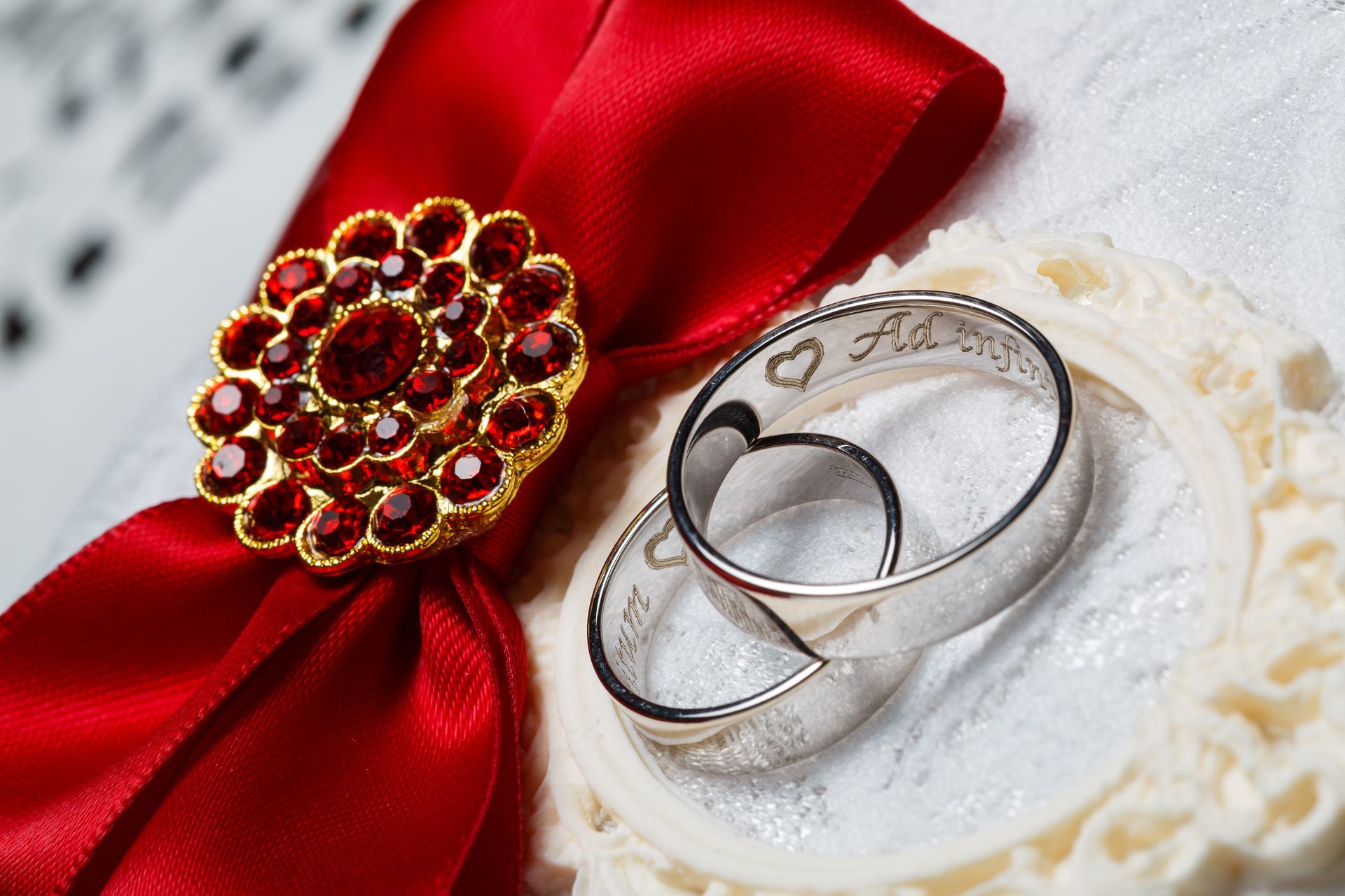 A pair of wedding rings sitting on top of a red ribbon.