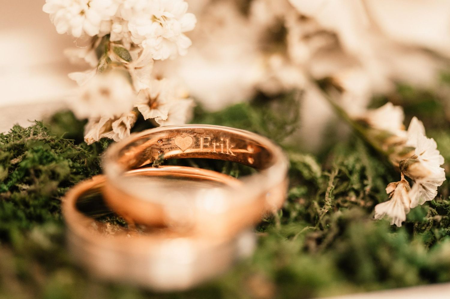 A pair of wedding rings sitting on top of a moss covered tray.