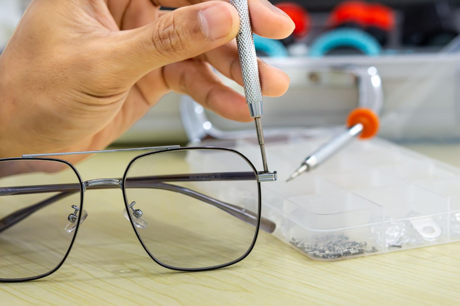 A person is fixing a pair of glasses with a screwdriver.