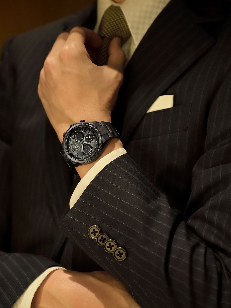 a man in a suit is adjusting his tie while wearing a watch