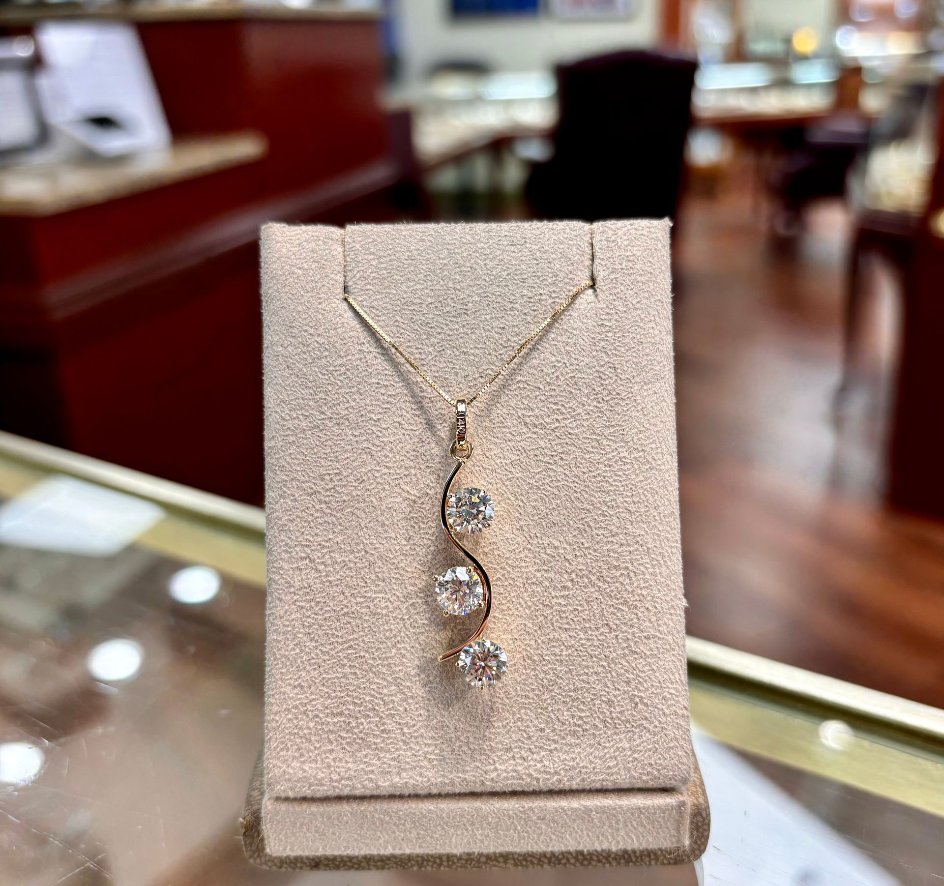 A necklace with three diamonds is on display in a store