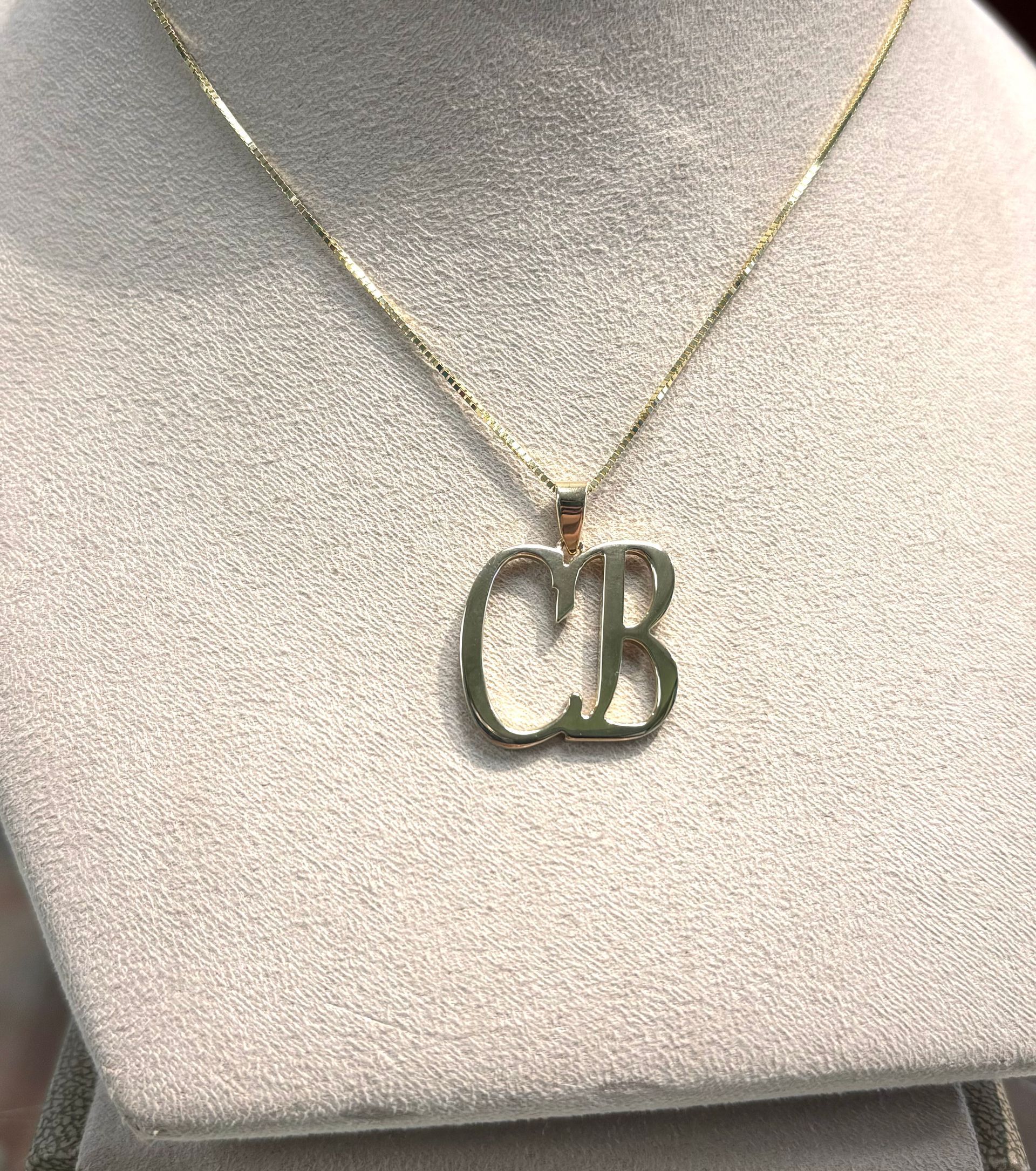 A close up of a necklace with a letter cb pendant on a mannequin.