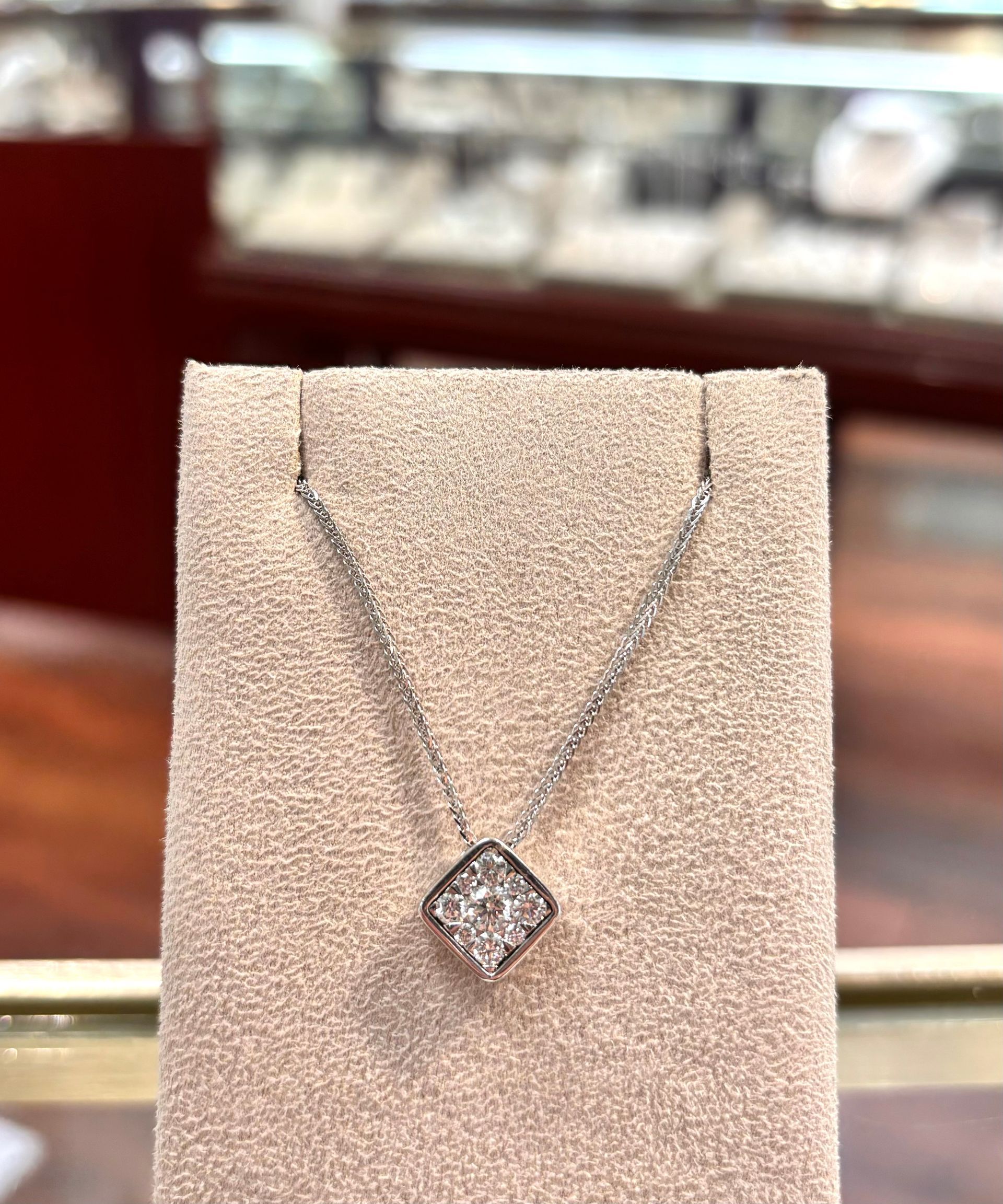 A diamond necklace is on display on a mannequin in a jewelry store.