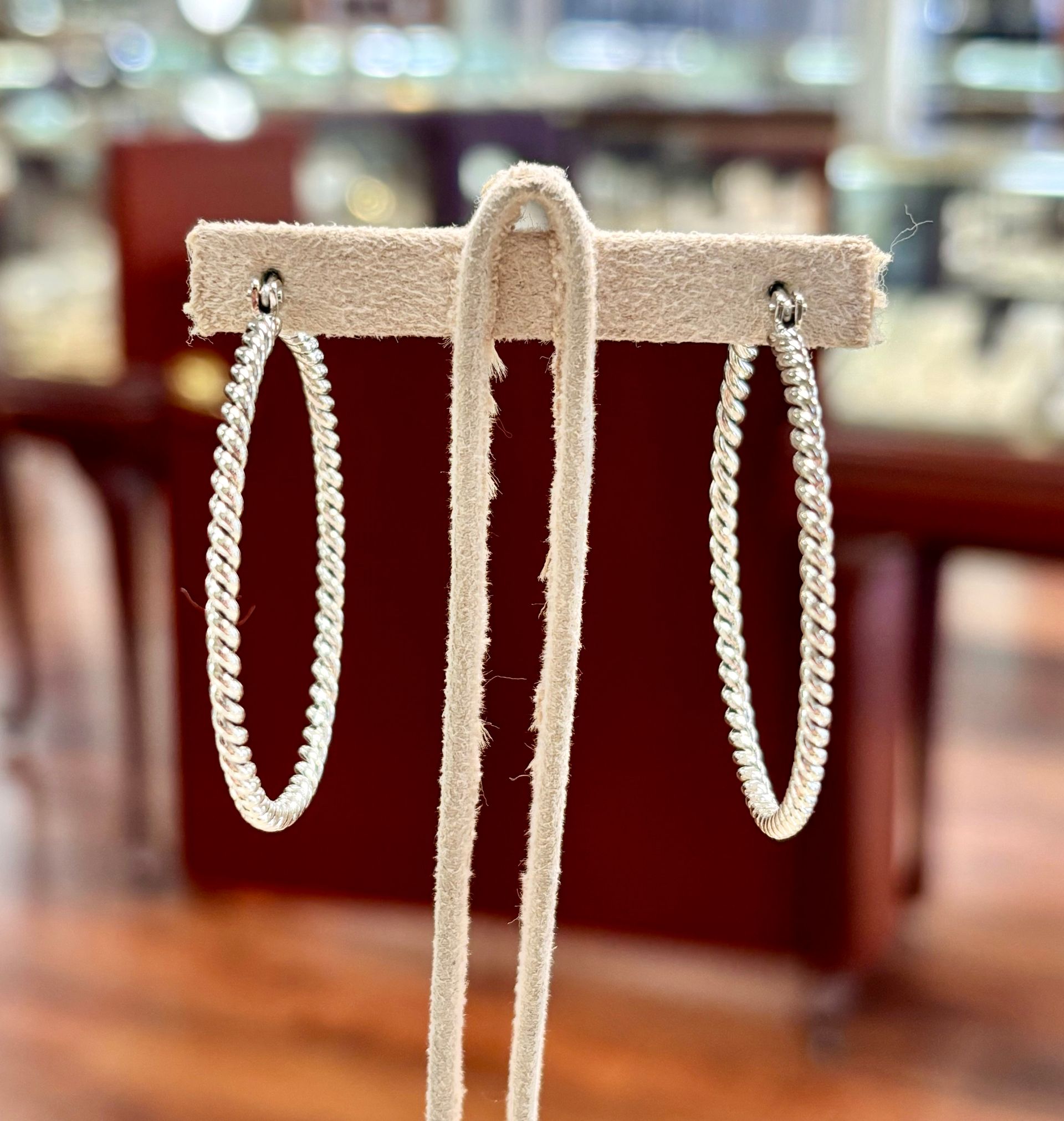 A pair of hoop earrings are sitting on a display stand.