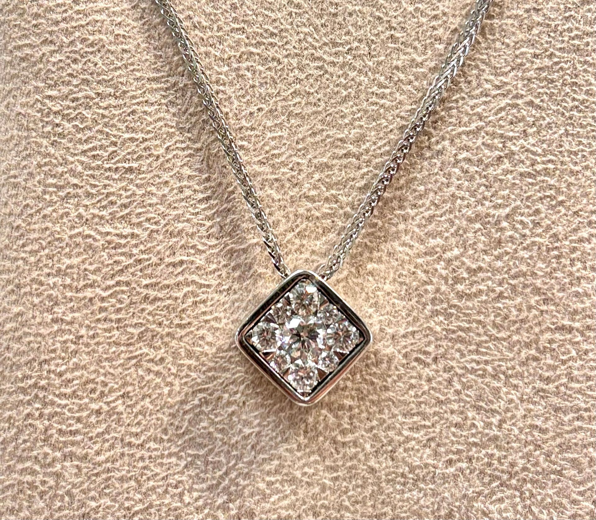 A necklace with a square diamond pendant on a chain.