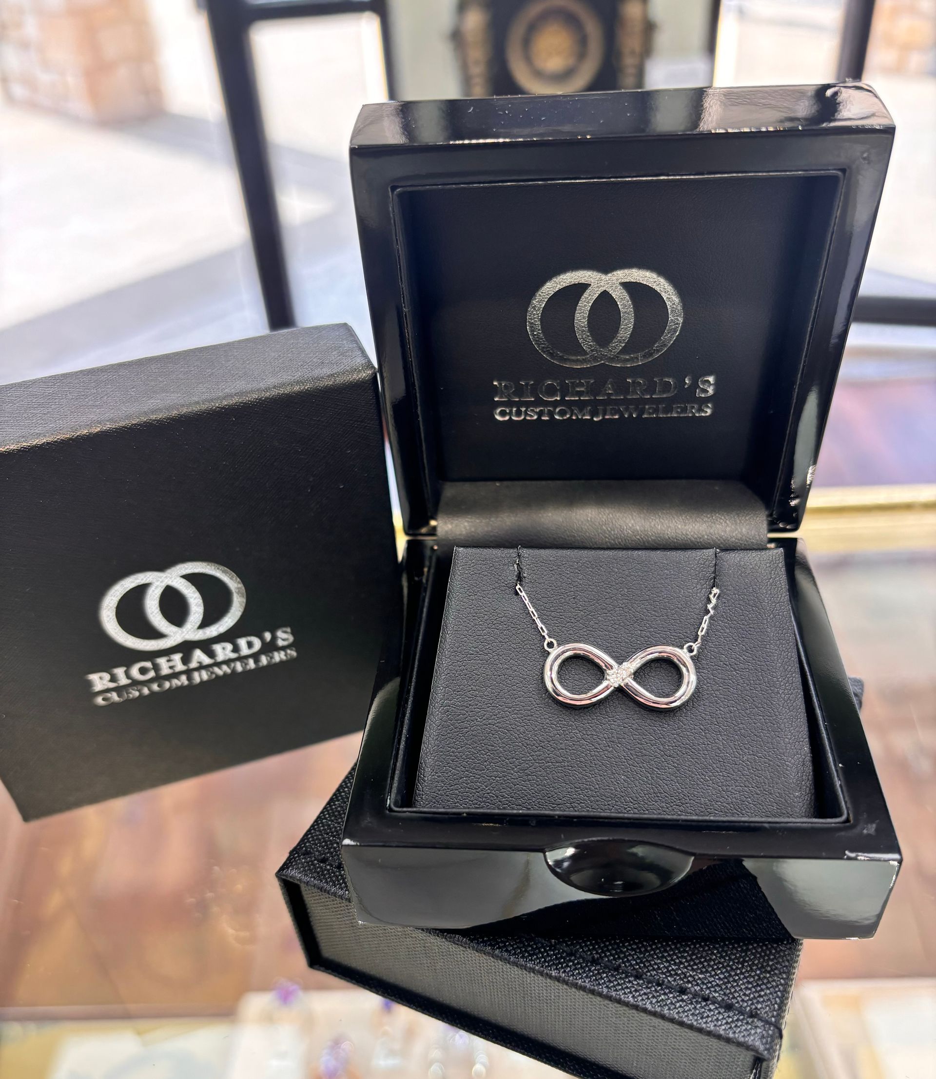 A necklace with an infinity symbol is in a black box