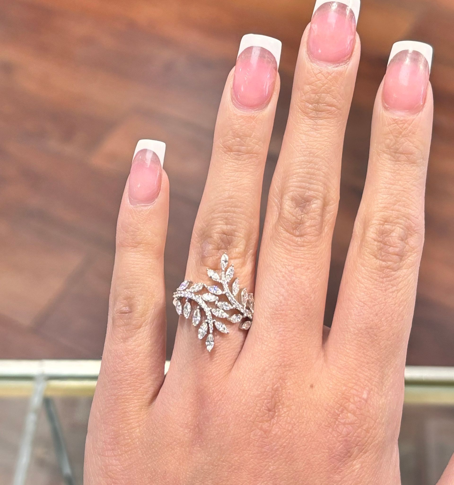A woman 's hand with pink nails and a silver ring