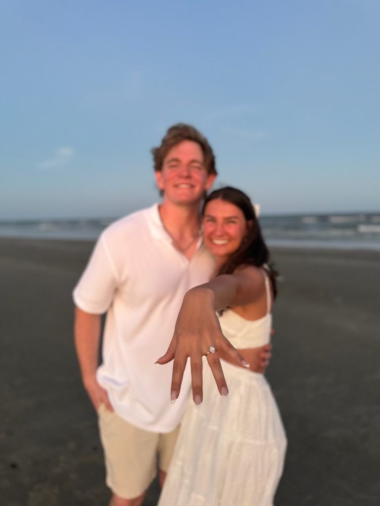 A man and a woman are posing for a picture on the beach
