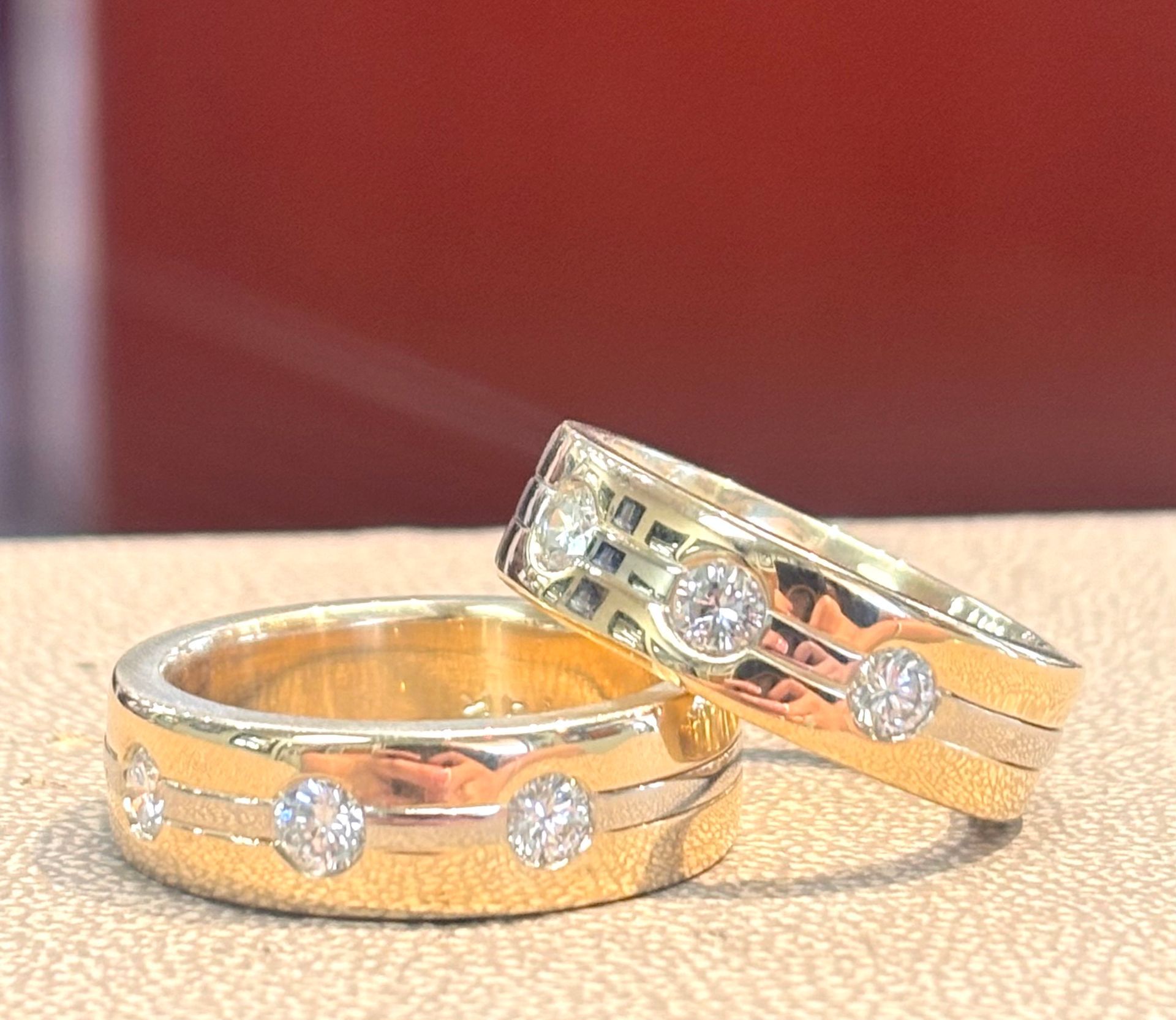 Two gold rings with diamonds on them are sitting on a table.