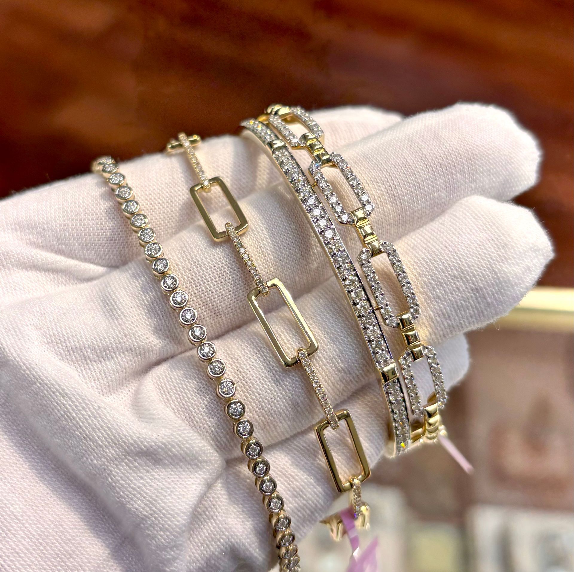 A hand wearing a white glove is holding three bracelets