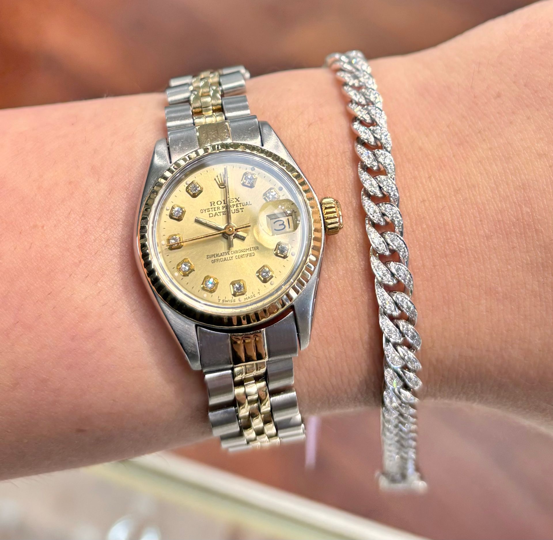 A woman is wearing a rolex watch and a diamond bracelet
