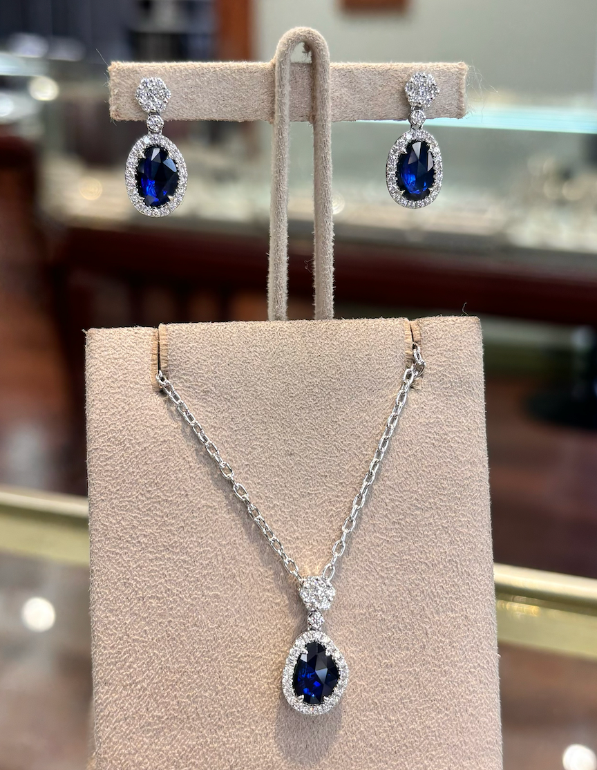 A necklace and earring set with sapphire and diamonds on display in a store.