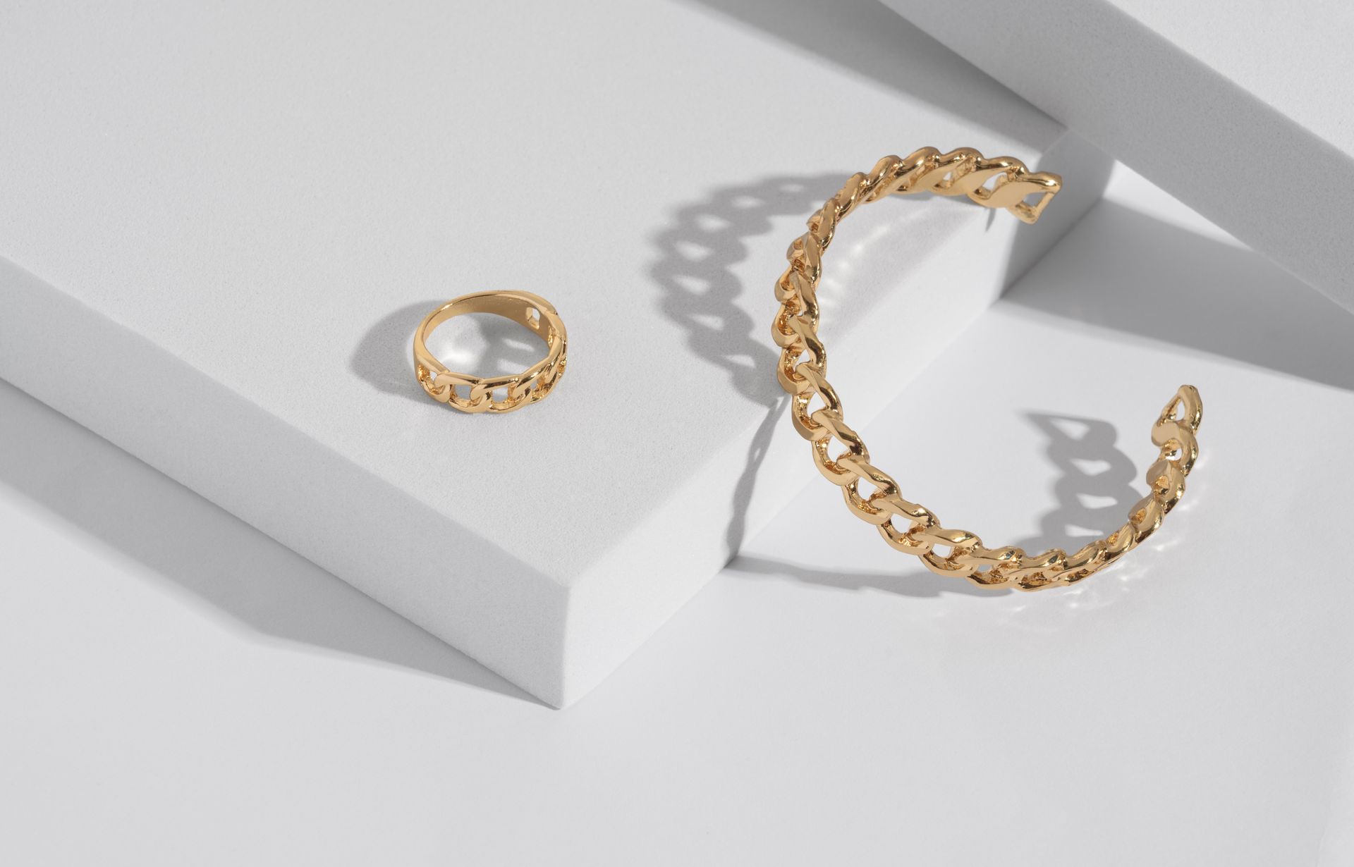 A bracelet and a ring are sitting on a white surface.