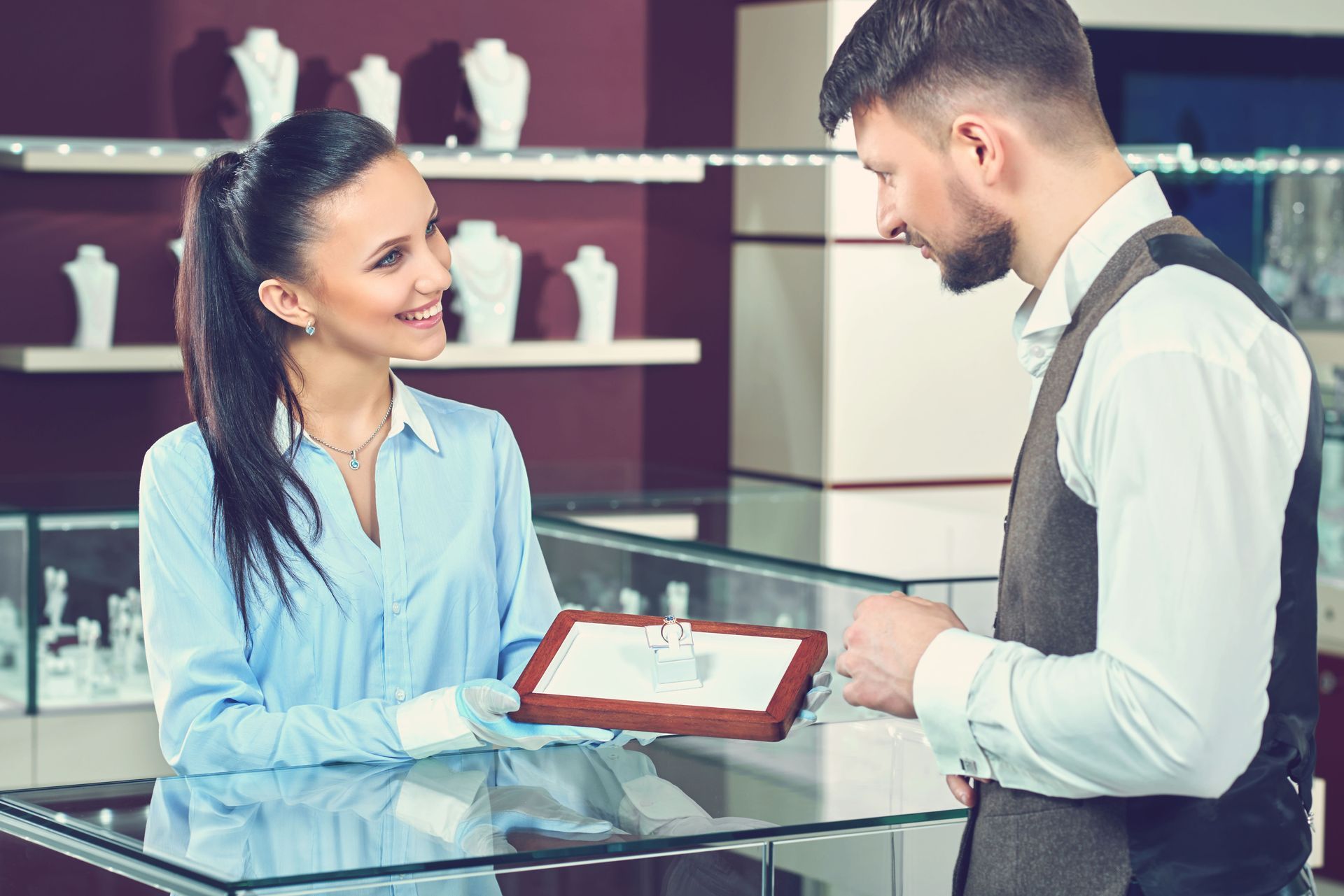 A man is buying a ring from a woman in a jewelry store.