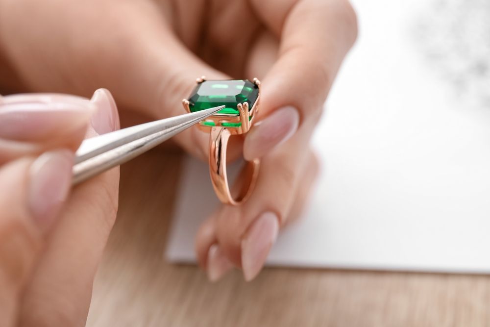 A woman is fixing a ring with tweezers.