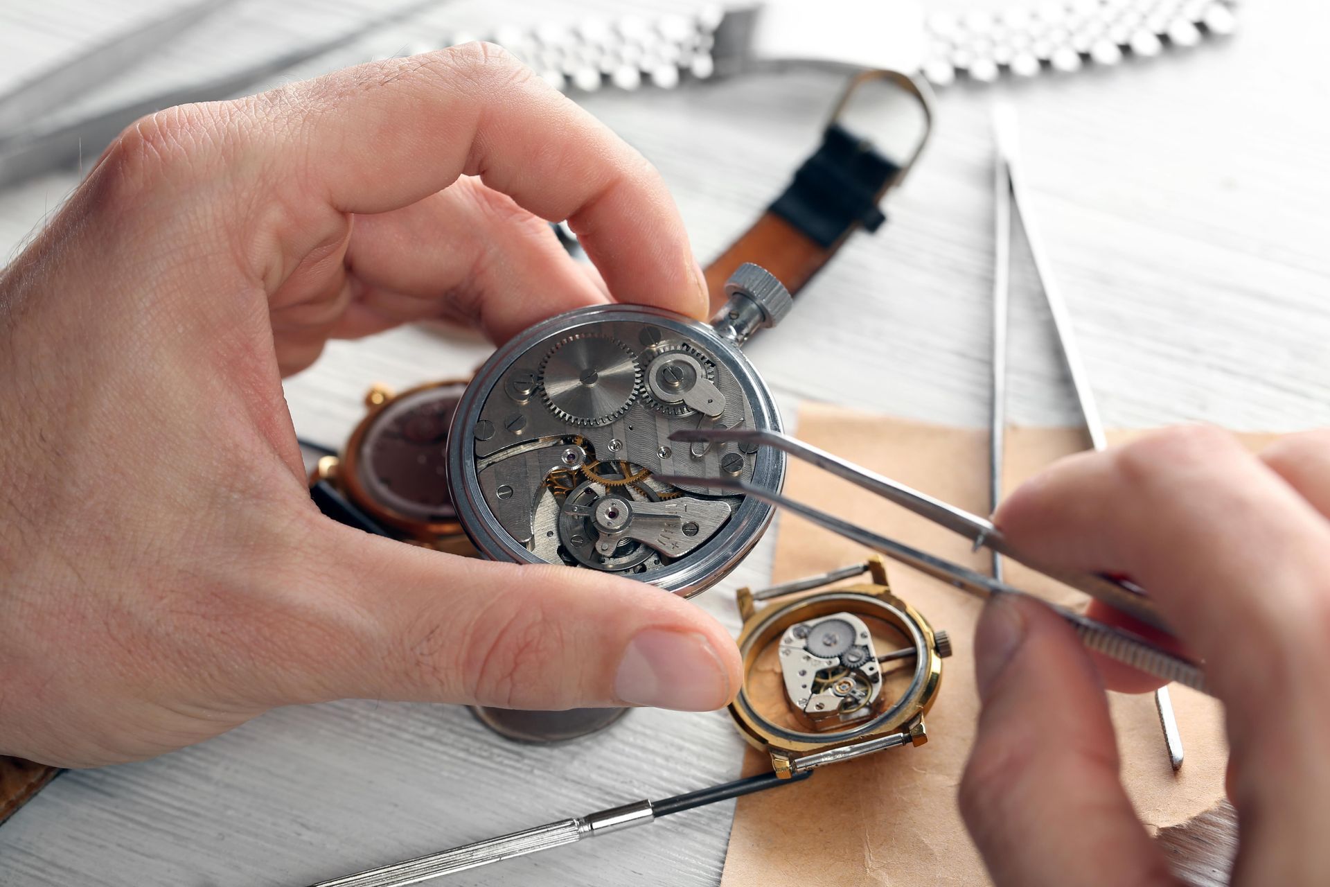 A person is fixing a watch with tweezers.